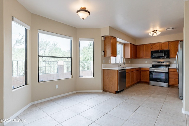 kitchen featuring visible vents, appliances with stainless steel finishes, brown cabinetry, light countertops, and baseboards