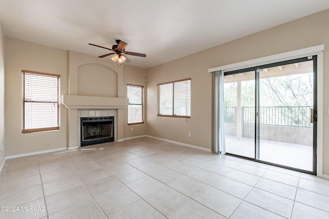 unfurnished living room featuring light tile patterned floors, a tiled fireplace, and baseboards