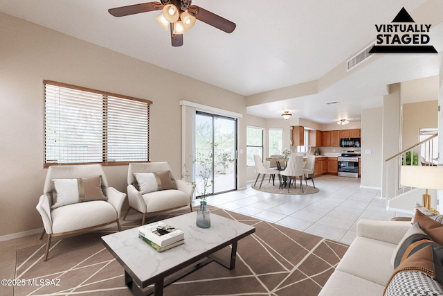 living room featuring light tile patterned floors, visible vents, baseboards, and ceiling fan