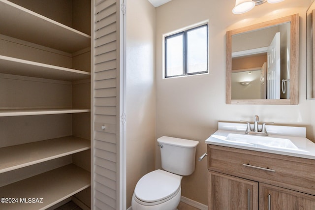 bathroom with a closet, toilet, and vanity