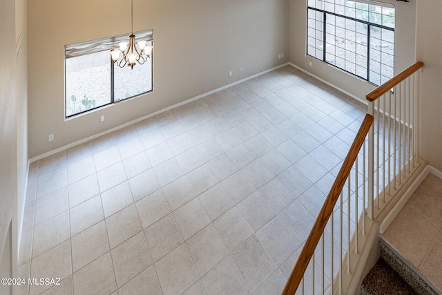 spare room featuring a notable chandelier, stairs, and baseboards