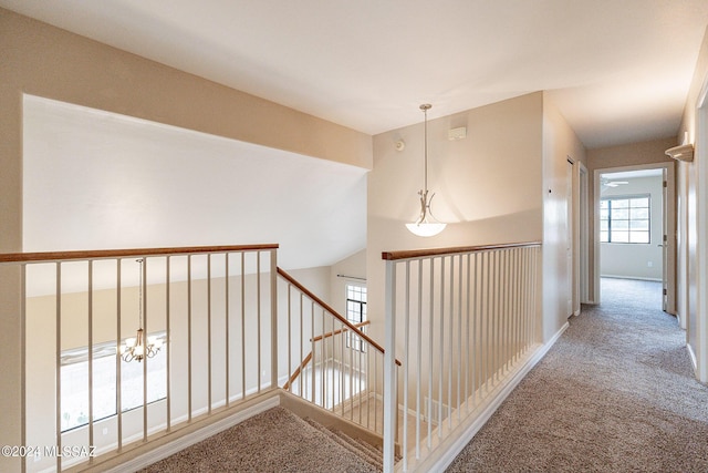 hall featuring an upstairs landing, baseboards, and carpet floors