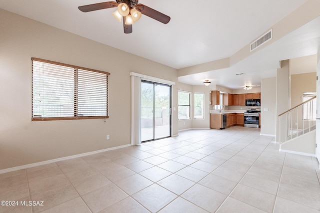 unfurnished living room with light tile patterned floors, visible vents, baseboards, and stairs