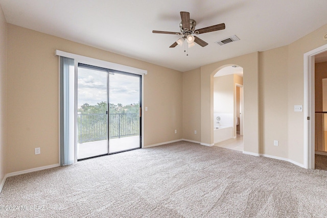 carpeted empty room featuring a ceiling fan, arched walkways, visible vents, and baseboards