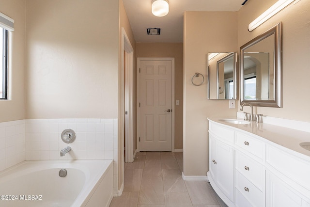 full bathroom featuring double vanity, baseboards, a garden tub, and a sink