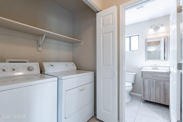 clothes washing area with washer and clothes dryer, light tile patterned floors, laundry area, and a sink