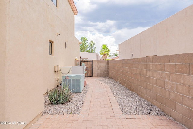 view of patio / terrace with a gate, central air condition unit, and fence