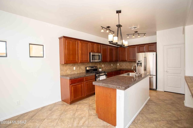 kitchen with appliances with stainless steel finishes, sink, backsplash, hanging light fixtures, and a center island with sink