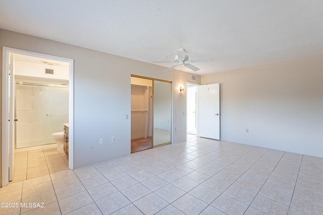 unfurnished bedroom with connected bathroom, light tile patterned floors, ceiling fan, and a closet