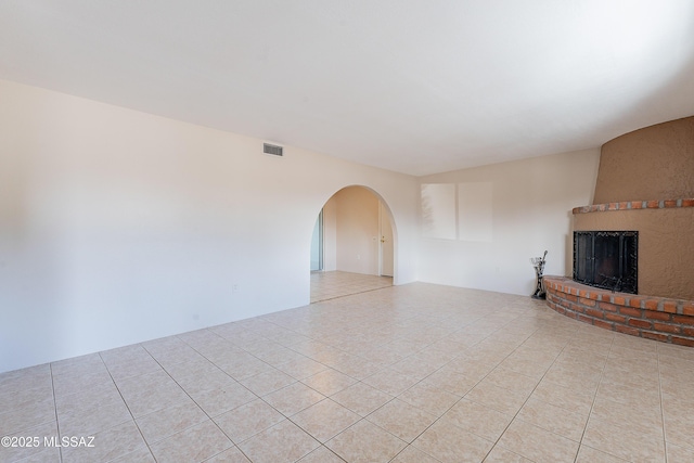 unfurnished living room with light tile patterned flooring and a fireplace