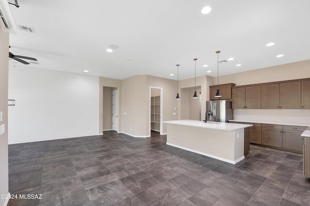 kitchen featuring pendant lighting, sink, ceiling fan, stainless steel refrigerator with ice dispenser, and an island with sink