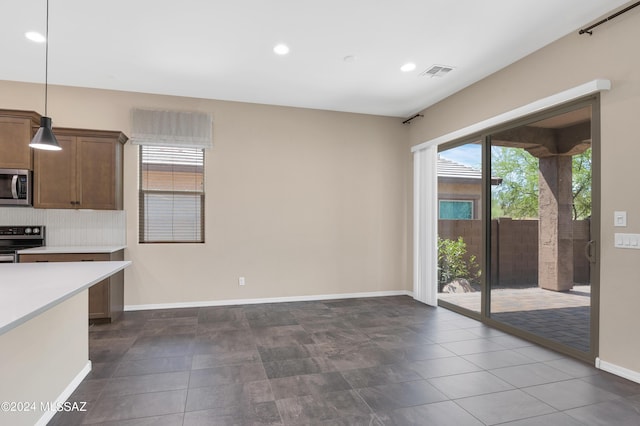 kitchen featuring stainless steel appliances, tasteful backsplash, and decorative light fixtures