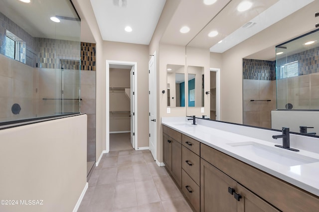 bathroom featuring tile patterned flooring, vanity, and a tile shower