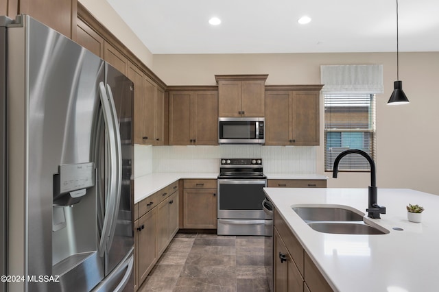 kitchen with stainless steel appliances, hanging light fixtures, sink, and backsplash