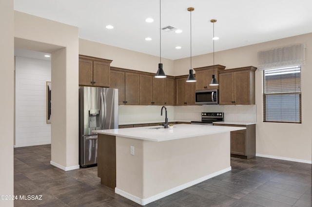 kitchen featuring sink, tasteful backsplash, pendant lighting, stainless steel appliances, and a kitchen island with sink