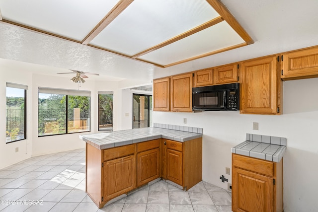 kitchen featuring tile counters, ceiling fan, light tile patterned floors, and kitchen peninsula