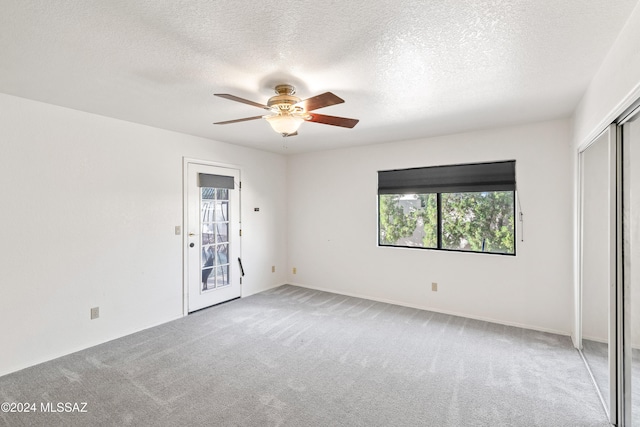 carpeted empty room featuring a textured ceiling and ceiling fan