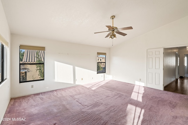 unfurnished room with plenty of natural light, ceiling fan, vaulted ceiling, and carpet