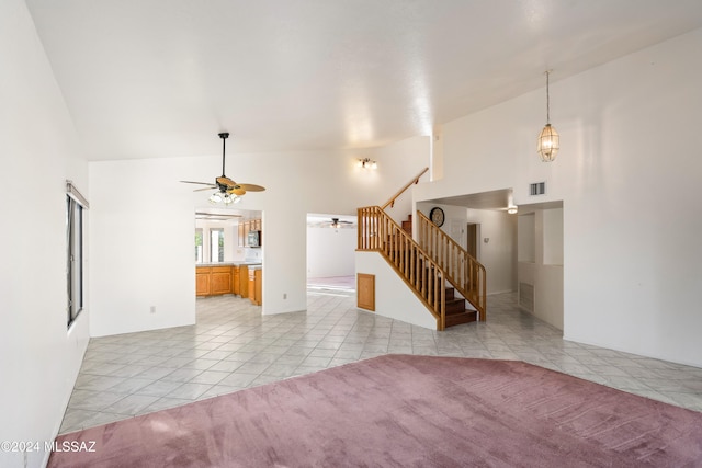 unfurnished living room with ceiling fan, vaulted ceiling, and light tile patterned floors