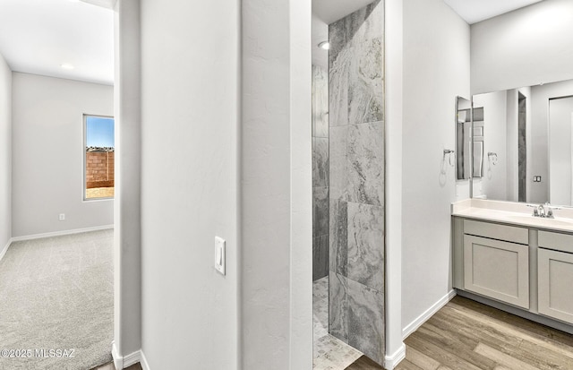 bathroom featuring a tile shower, vanity, and hardwood / wood-style floors