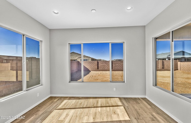 unfurnished room featuring a healthy amount of sunlight and hardwood / wood-style floors