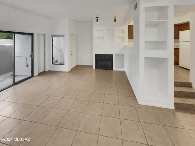 unfurnished living room with built in shelves and light tile patterned floors