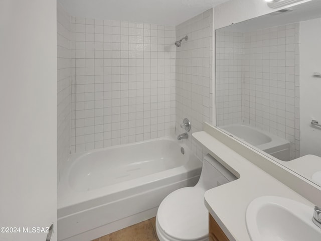 full bathroom featuring vanity, tiled shower / bath combo, and toilet