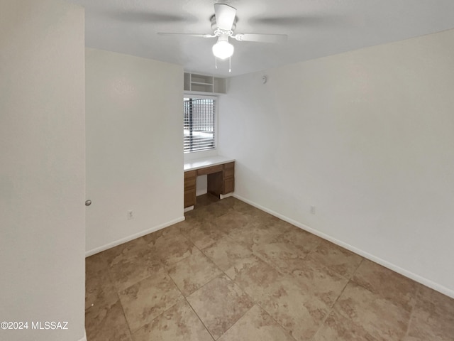 empty room with ceiling fan and built in desk