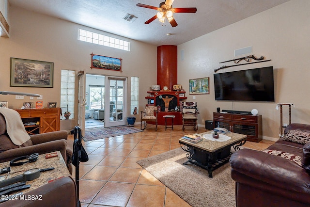 living room with light tile patterned floors, baseboards, visible vents, a ceiling fan, and a high ceiling