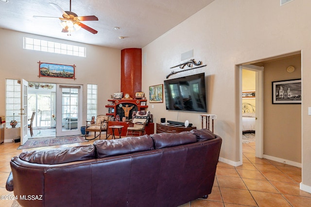 living room featuring ceiling fan, a high ceiling, baseboards, and light tile patterned flooring