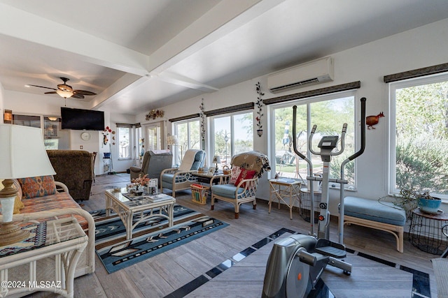 living area with a wall unit AC, wood finished floors, beam ceiling, and a ceiling fan