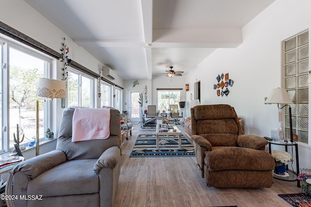 living area featuring wood finished floors, ceiling fan, beam ceiling, and a wall mounted AC