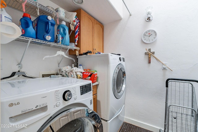 laundry area featuring a textured wall, separate washer and dryer, cabinet space, and baseboards