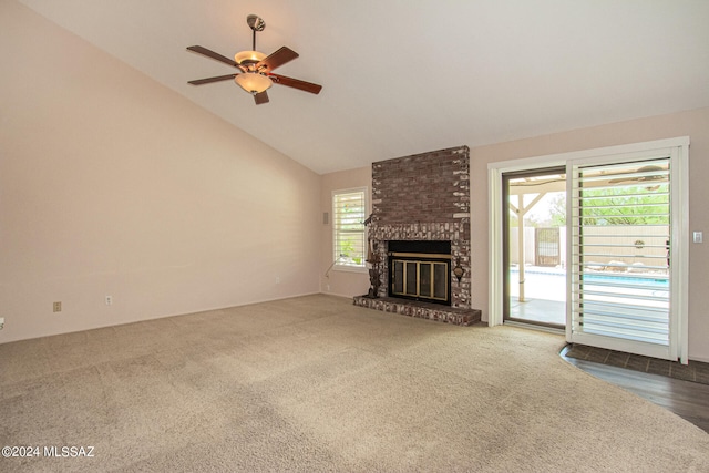 unfurnished living room with high vaulted ceiling, dark colored carpet, ceiling fan, and a brick fireplace