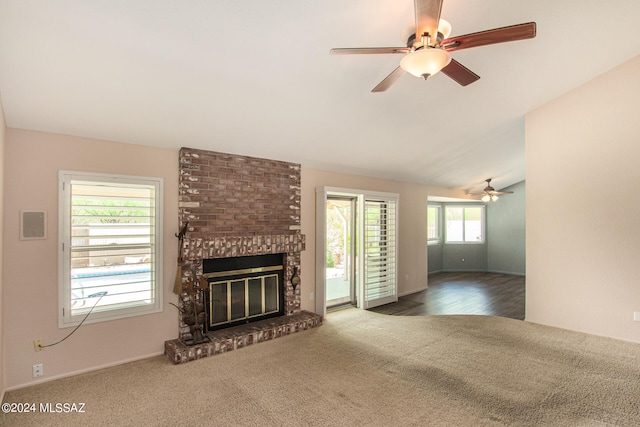 unfurnished living room with ceiling fan, lofted ceiling, a brick fireplace, and hardwood / wood-style floors