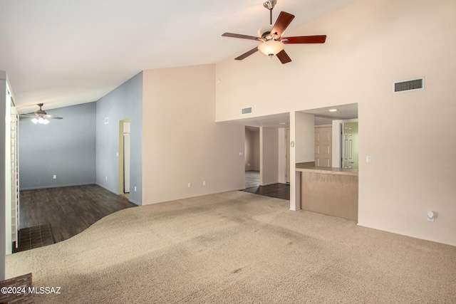 unfurnished living room with high vaulted ceiling, ceiling fan, and dark carpet