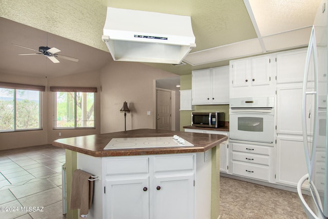 kitchen with white cabinets, white appliances, a kitchen island, light tile patterned floors, and ceiling fan