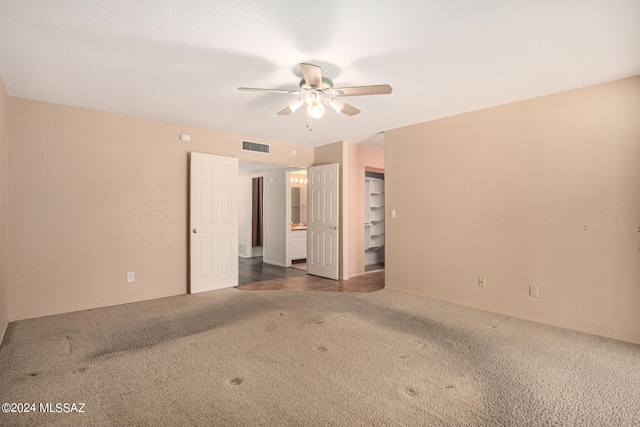 unfurnished bedroom featuring a closet, ceiling fan, a walk in closet, and carpet floors