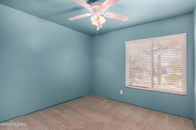 carpeted empty room featuring ceiling fan and a textured ceiling