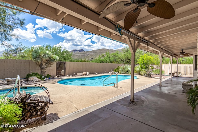 view of swimming pool featuring a mountain view, ceiling fan, and a patio area