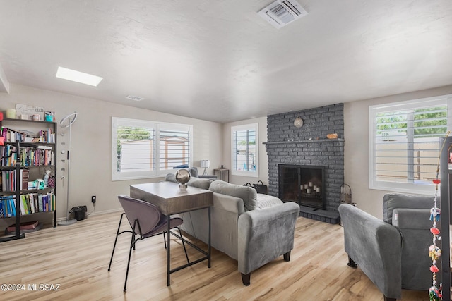 living room with lofted ceiling, a brick fireplace, and light wood-type flooring