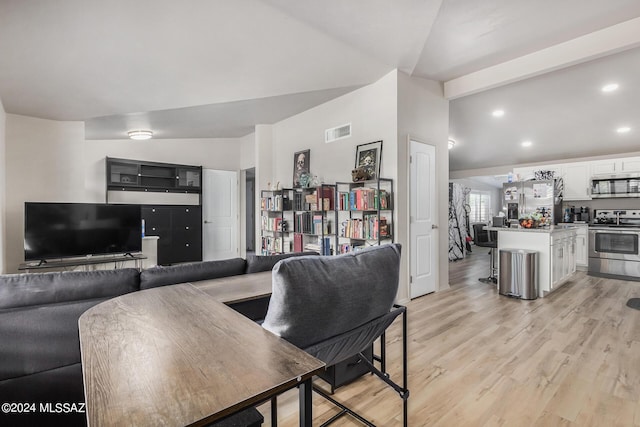 living room featuring lofted ceiling and light hardwood / wood-style floors