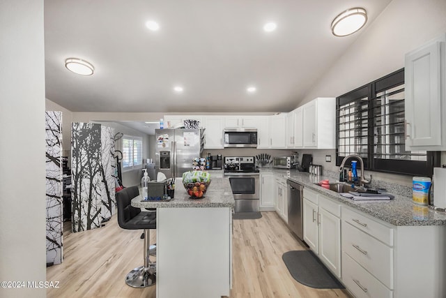 kitchen with white cabinets, stainless steel appliances, a center island, and a kitchen bar