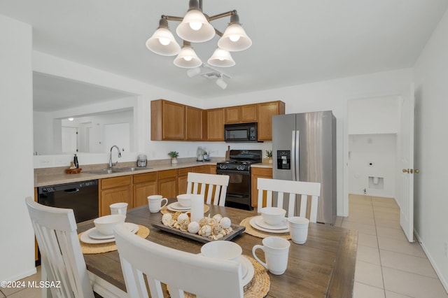 kitchen with sink, light tile patterned floors, a notable chandelier, pendant lighting, and black appliances