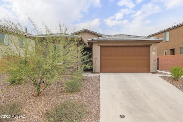 view of front of property with a garage, driveway, a tiled roof, and stucco siding