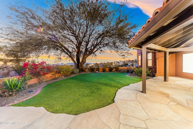 yard at dusk featuring a patio area