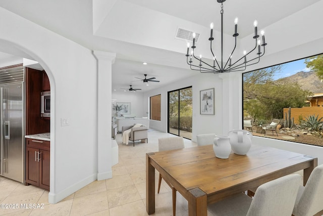 dining area with light tile patterned flooring, plenty of natural light, and ceiling fan with notable chandelier