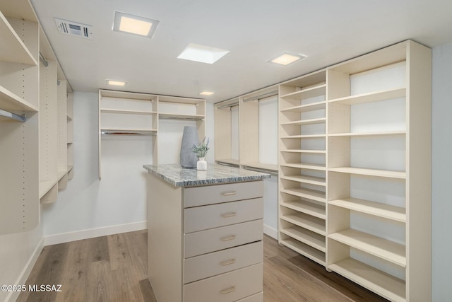 walk in closet with light hardwood / wood-style flooring