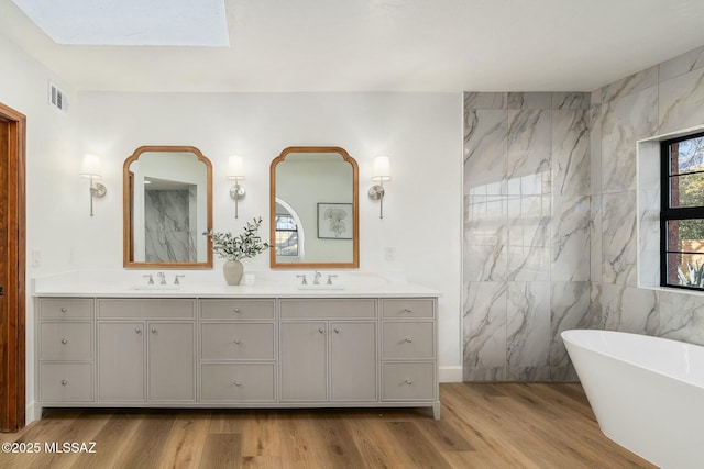 bathroom with hardwood / wood-style flooring, vanity, tile walls, and a washtub