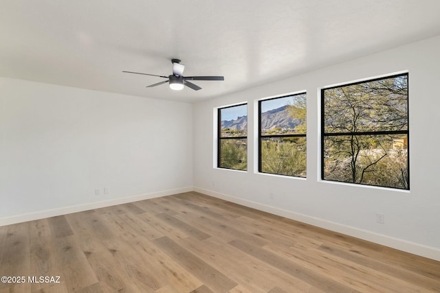 empty room with ceiling fan and light hardwood / wood-style flooring